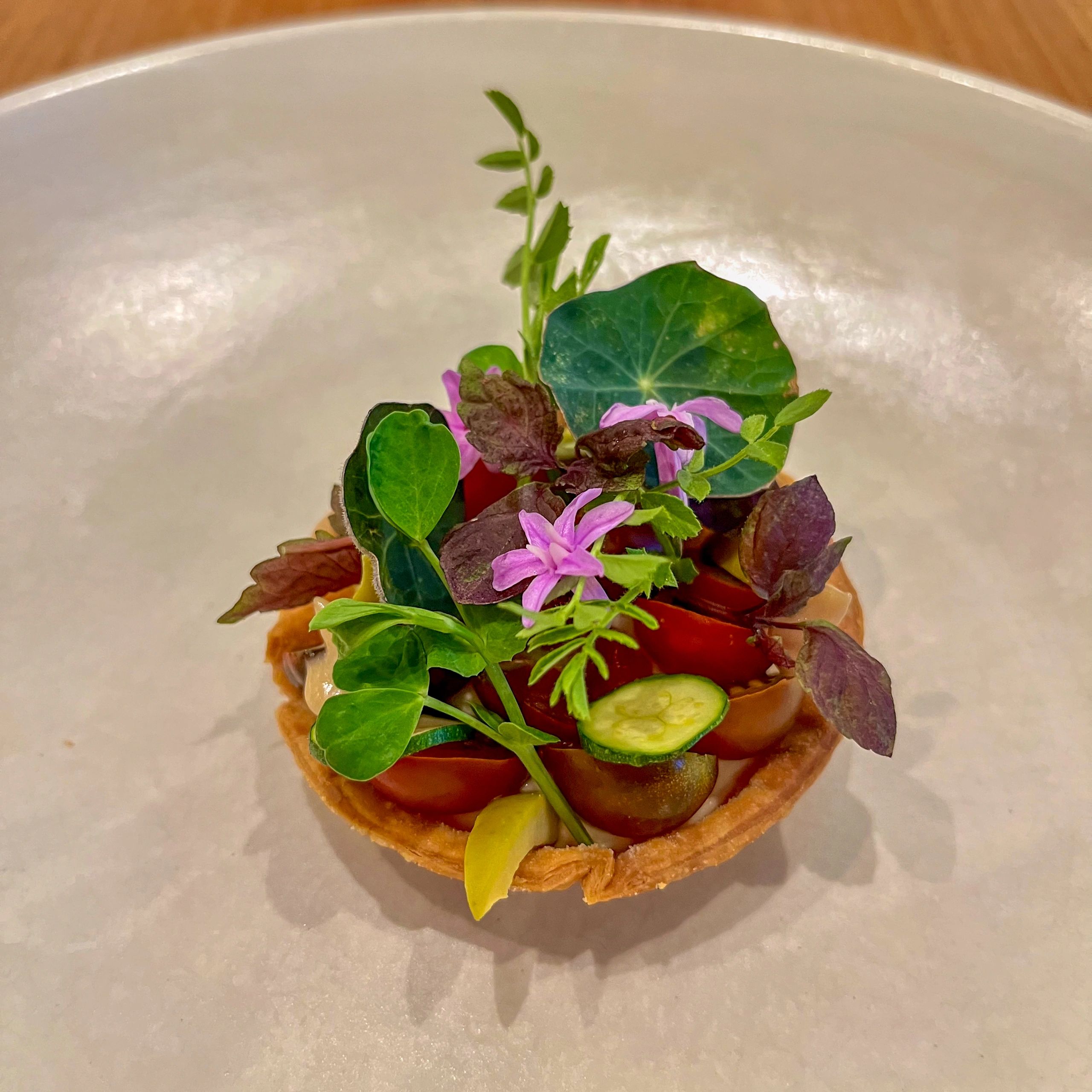 Gourmet savoury tartlet with heirloom tomatoes and edible flowers